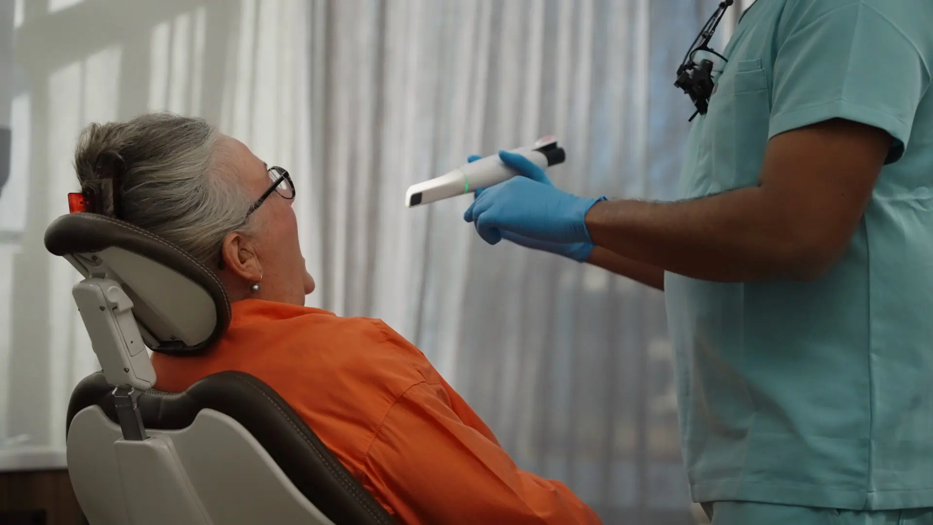 Dr Sri with an intraoral scanner beside a patient in the chair