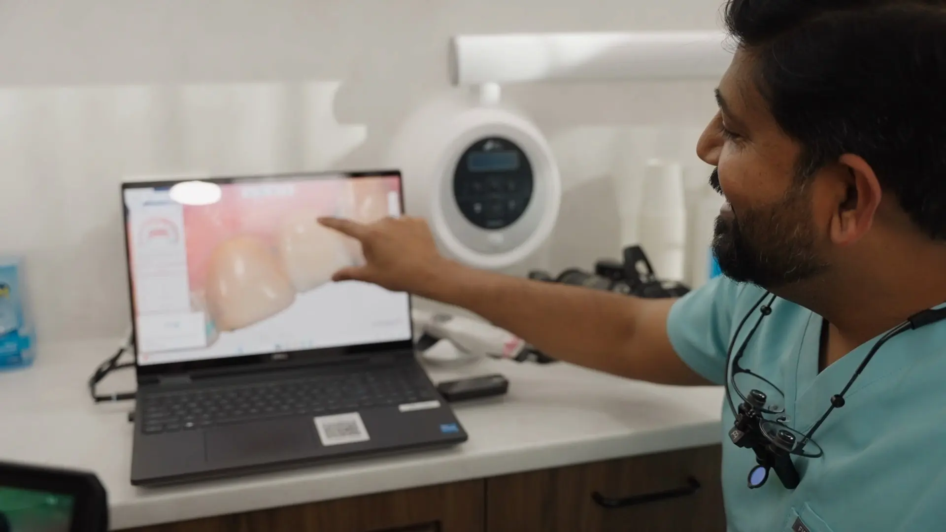 Dr Sri pointing at a crown design on a laptop screen