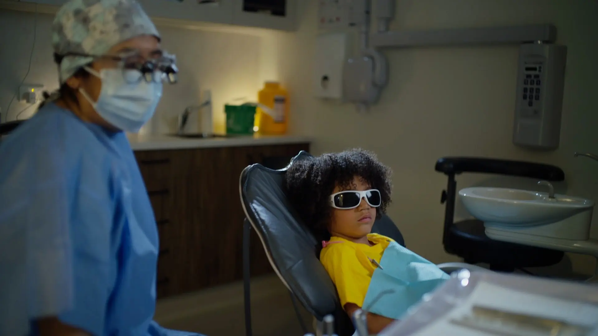 A child in the dental chair wearing protective sunglasses