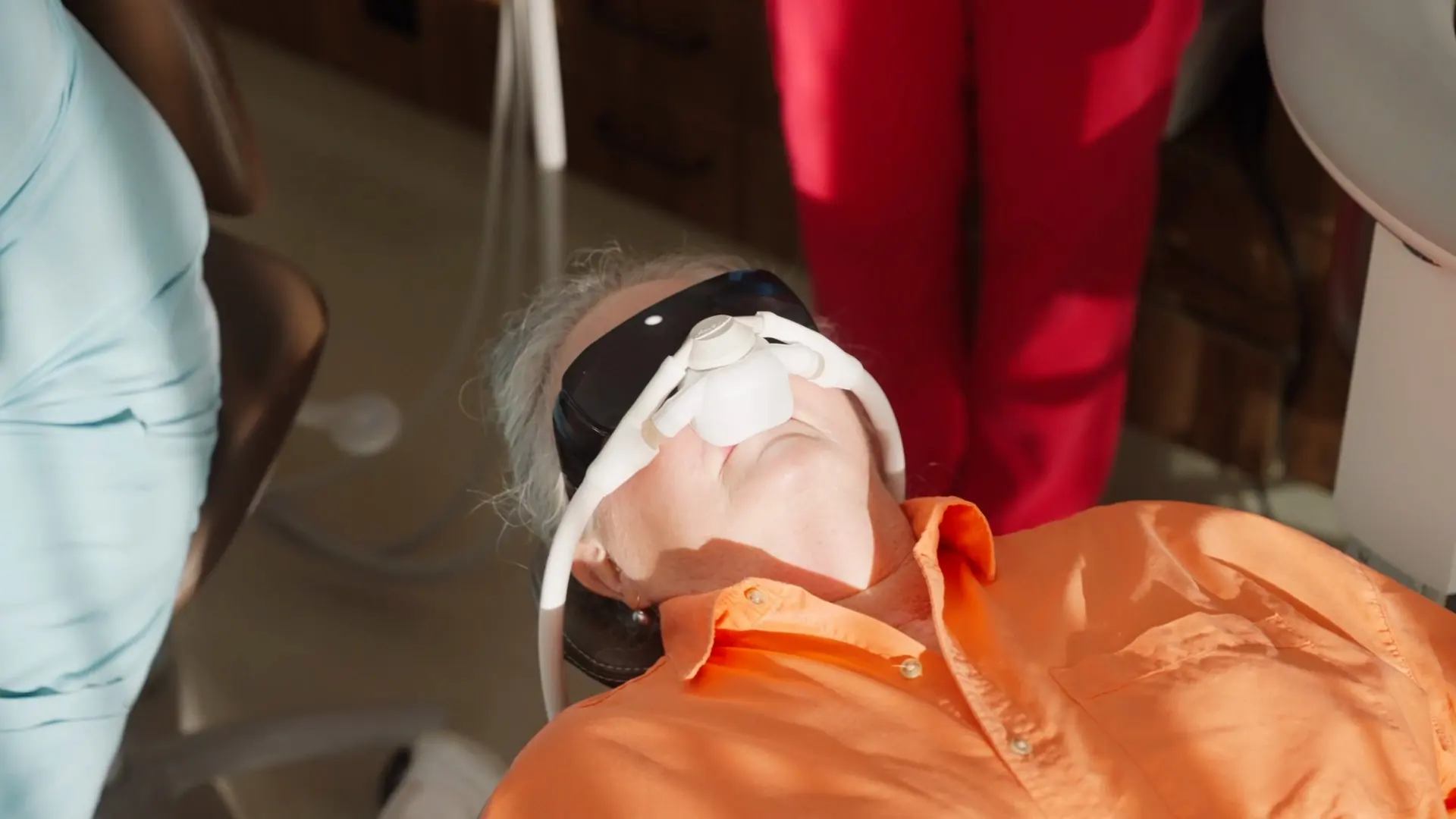 A patient reclined in the dental chair wearing a nasal hood